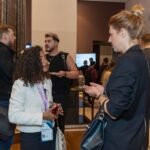 Attendees networking and engaging in conversations at a professional technology conference, highlighting collaboration and connection.